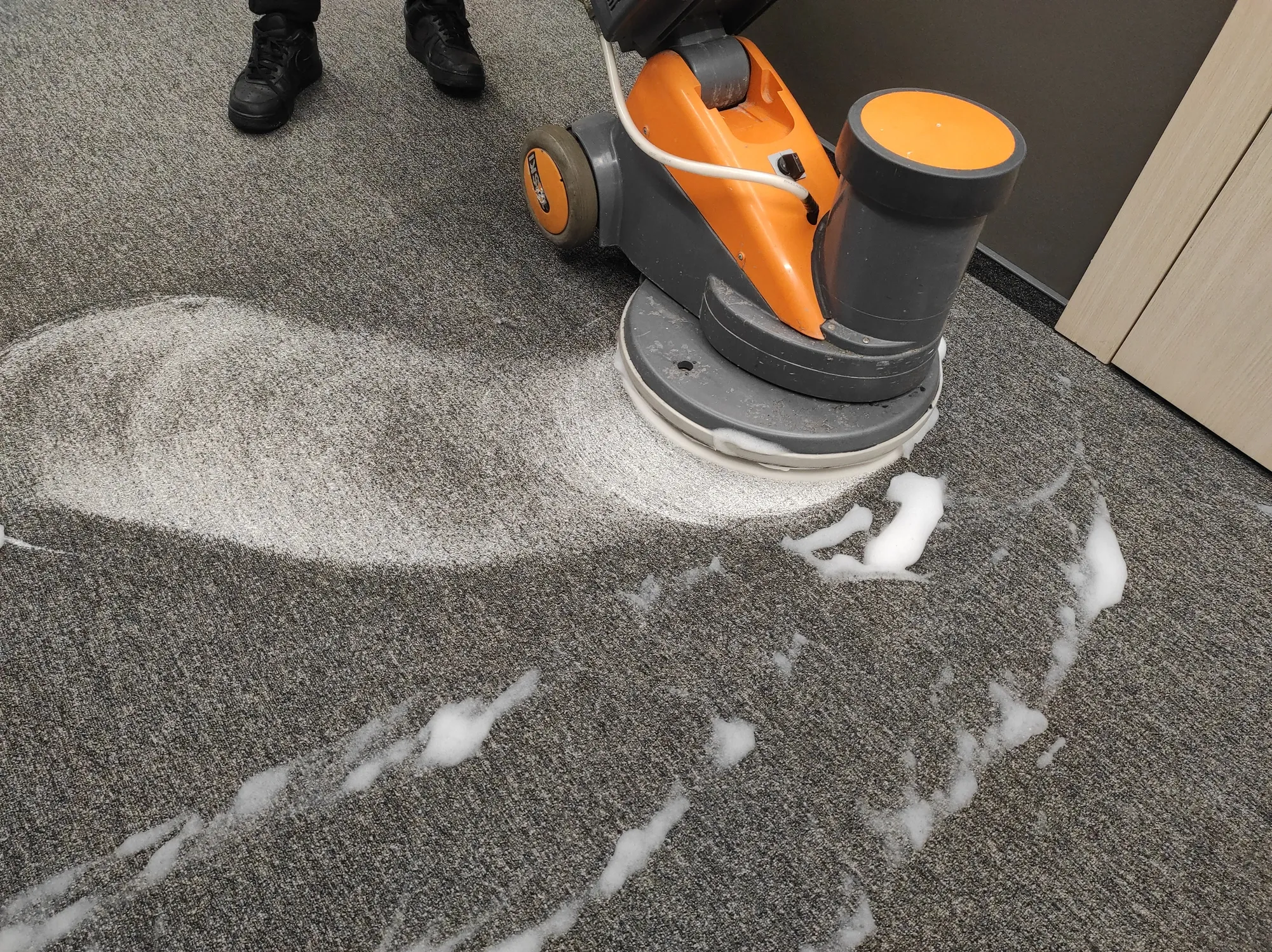 Floor cleaning machine removing carpet stains during a professional cleaning service