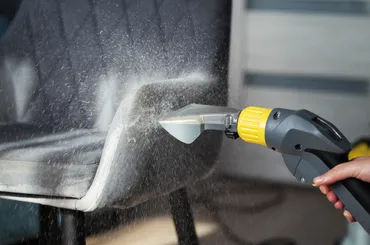 Upholstery cleaning on a quilted grey armchair with handheld tool