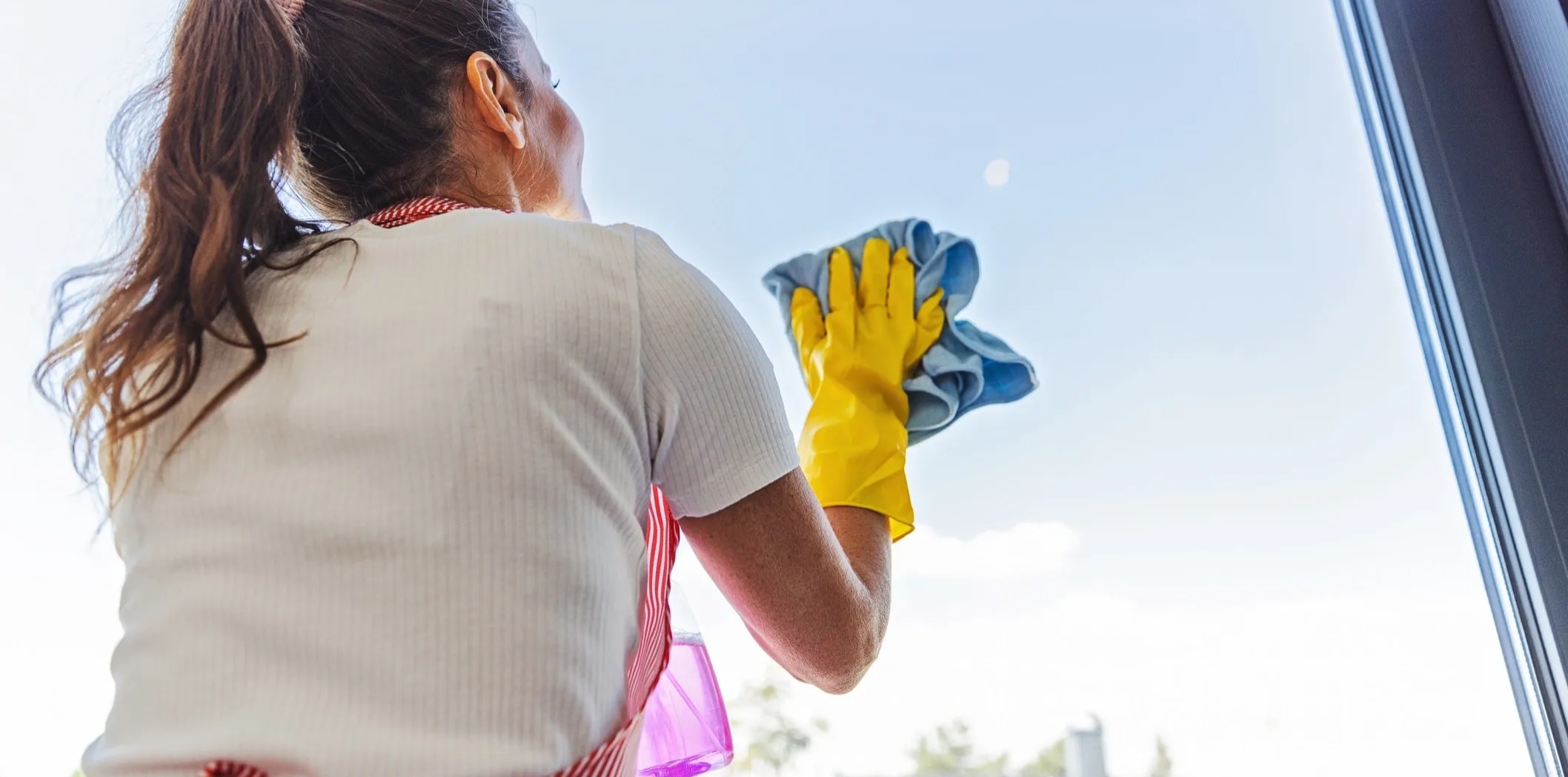 Professional cleaner cleaning interior windows inside a bright Perth home